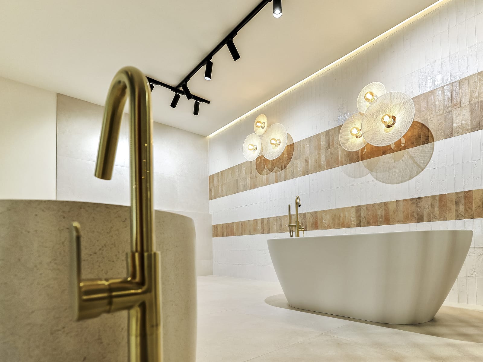 Detalle de grifería de latón cepillado y bañera exenta en el showroom