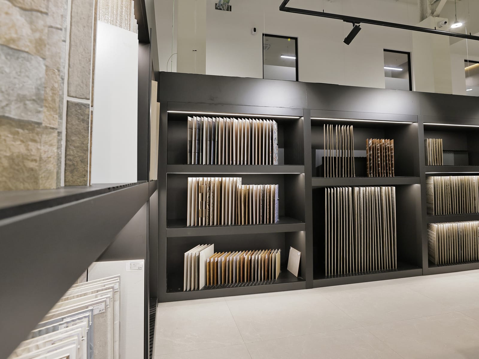 Materioteca del showroom con estanterías negras de muestras cerámicas