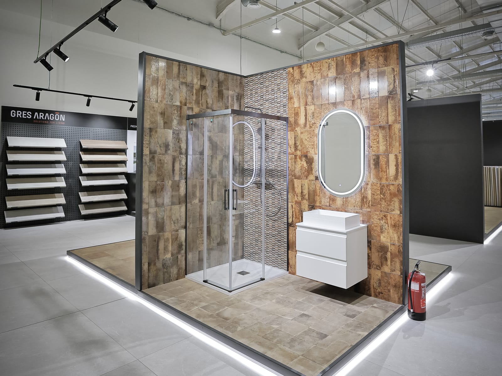 Ducha del showroom con revestimiento de piedra cálida, mampara y mueble blanco