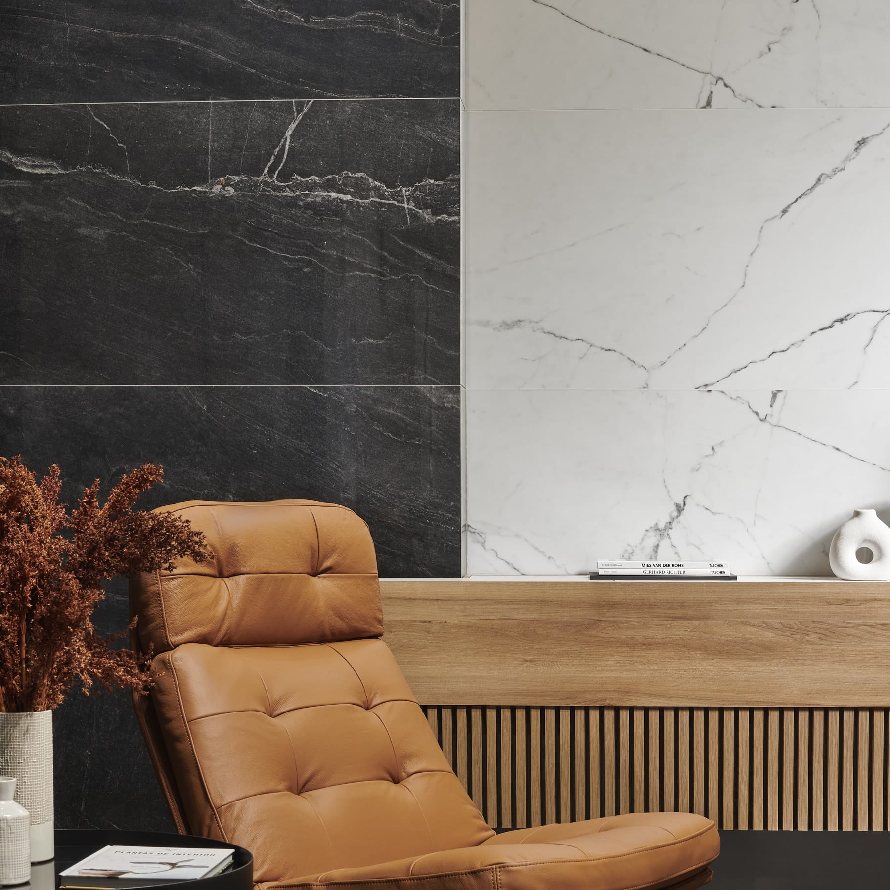 Pared de porcelánico efecto mármol negro y blanco junto a un sillón de cuero