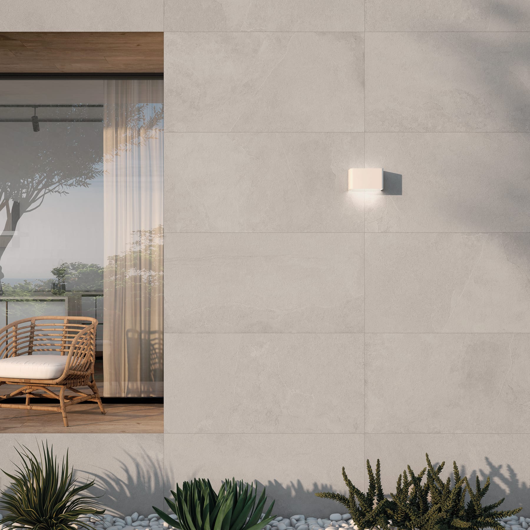 Muro exterior revestido con porcelánico claro de gran formato y plantas