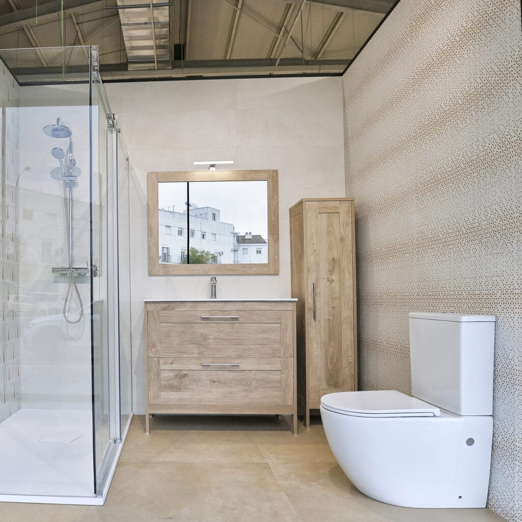 Baño completo del showroom con ducha, mueble de madera, espejo y sanitario