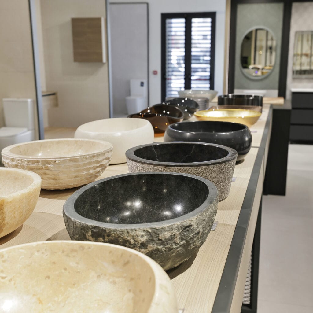 Mesa del showroom con lavabos de piedra en distintos acabados y colores