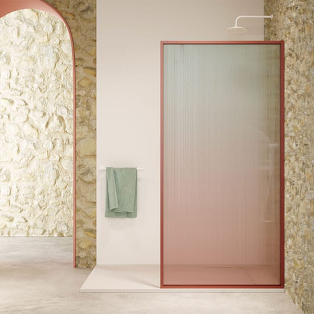 Mampara de ducha con vidrio acanalado y perfil rosa junto a pared de piedra