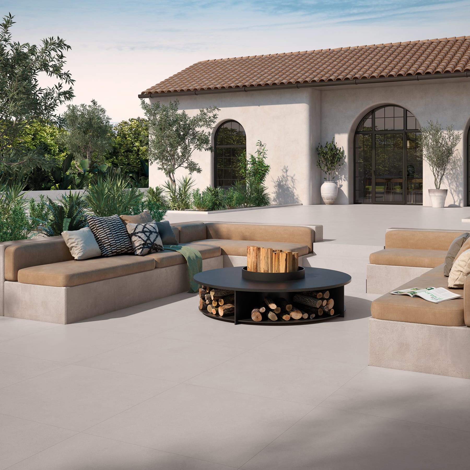 Terraza mediterránea con suelo de exterior claro, sofás y mesa de fuego
